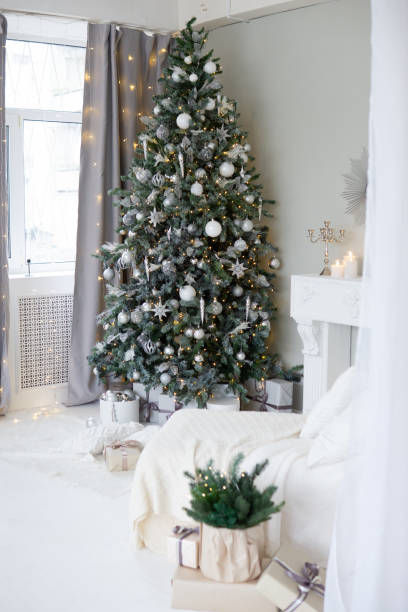 istock Bright interior with a false fireplace decorated for Christmas. Christmas trees with garlands, balloons and lights. 1811138053