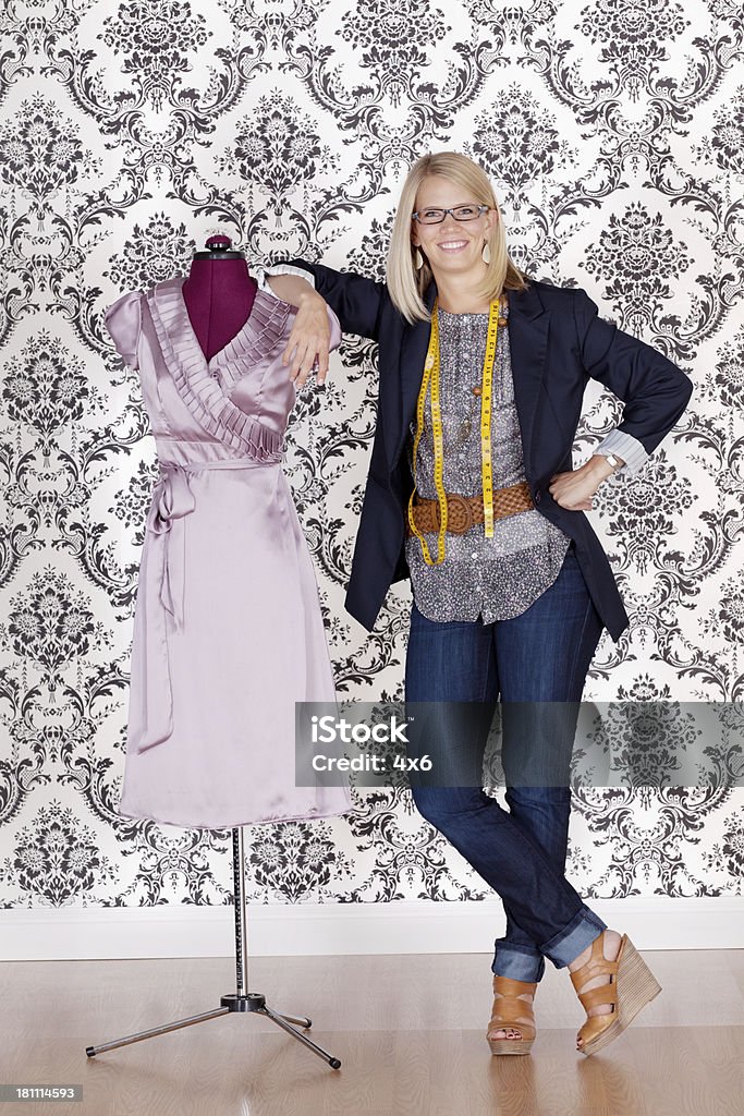 Sorridente fashion designr steanding vicino a un manichino - Foto stock royalty-free di Abbigliamento casual