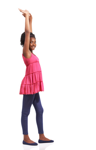 Full length studio portrait of a young african american girl standing with her arms raised isolated on white