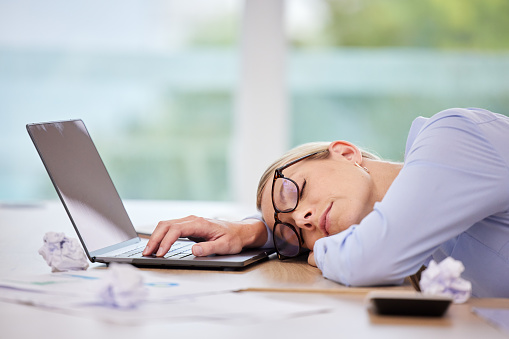 Business woman sleeping at laptop desk, burnout stress from corporate and insomnia problem in workplace at computer. Office worker tired, loss of energy and overworked person nap at tech company job