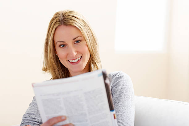 istock Young woman reading a magazine on sofa 181116374