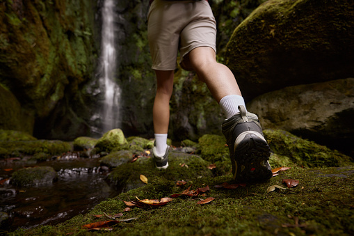 Close up of unrecognizable hiker walking through nature by the waterfall. Copy space.