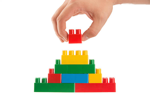 Close up of hand placing the top block onto a toy pyramid stock photo