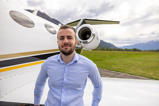 Young corporate businessman on tarmac near private jet plane
Portrait, he faces the camera