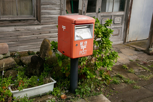 Ogi, Japan; 1st October 2023: Red Japanese mailbox on a street in the city of Oji on the island of Sado.