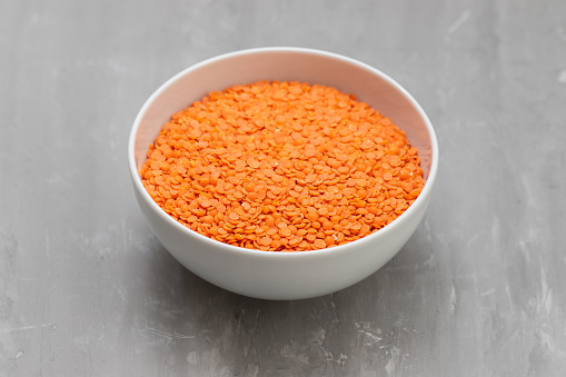 uncooked Red lentils in white small bowl on ceramic
