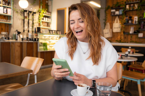 istock Beautiful young woman using smartphone in coffee shop 1811178375