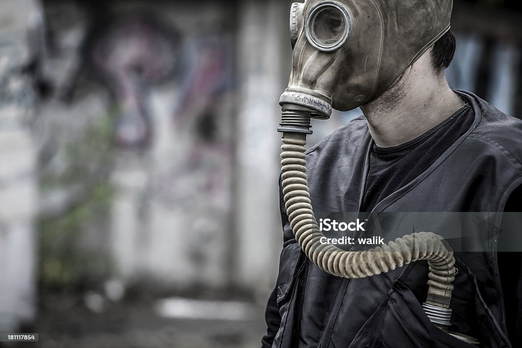 Man wearing gas mask with copy space Destroyed industrial building and Man with gas mask standing at the foreground. Adult Stock Photo