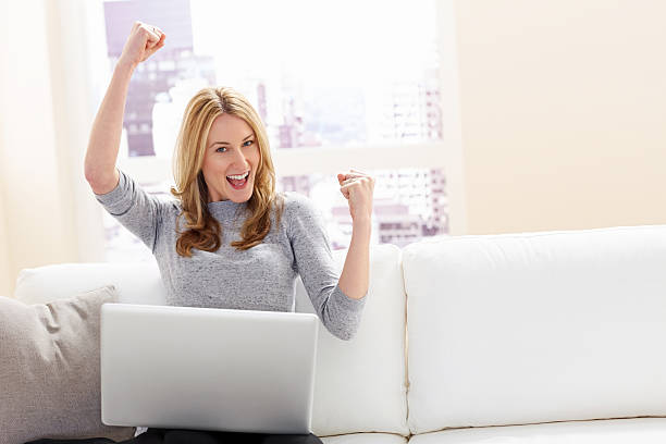 istock Winner - Happy young female using laptop at home 181117878