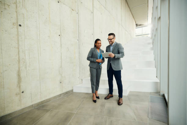 Happy business colleagues working on touchpad in a hallway.