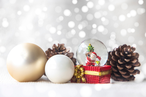 Christmas balls, Santa Claus in a Snow globe, and Pine cones on a white Cloth, set Against a Red Background and exquisite bokeh. New Year Celebration Atmosphere, about of Important day.