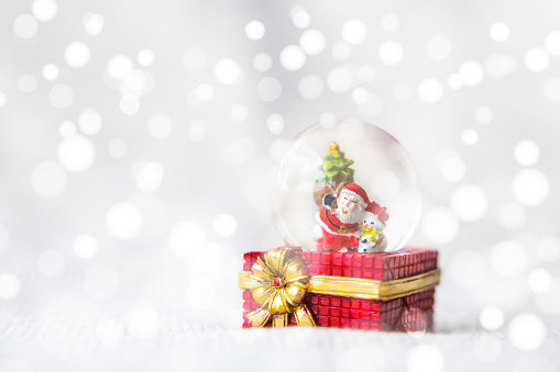 Christmas balls, Santa Claus in a Snow globe, and Pine cones on a white Cloth, set Against a Red Background and exquisite bokeh. New Year Celebration Atmosphere, about of Important day.