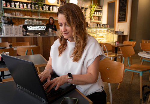 Smiling woman using laptop at cafe