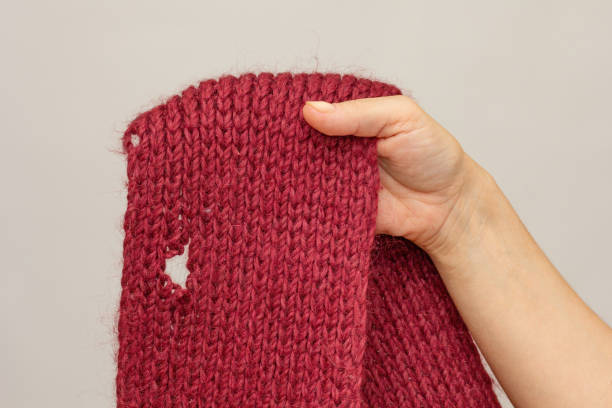 istock Woman hand holding knitted thing with hole made by moth 1811185684