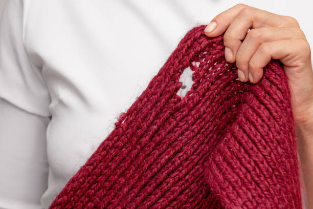 istock Woman hand holding knitted thing with hole made by moth 1811186913
