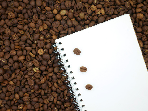 Book on coffee beans texture background. Paper for notes. Top view.