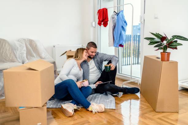 Happy pregnant couple talking after moving into a new home. Happy expecting couple communicating while going through housing plans after moving into a new apartment. fresh start stock pictures, royalty-free photos & images