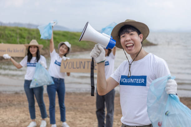 istock Young man holding megaphone or microphone talking invitation notice to campaign to save the global environment. clean up garbage in tourist attractions. Conservation and care cleanliness in nature. 1811194466