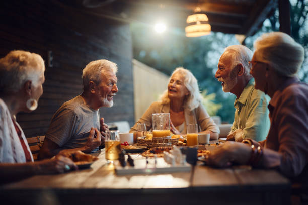 istock Group of happy seniors talking at picnic table on a patio. 1811197329