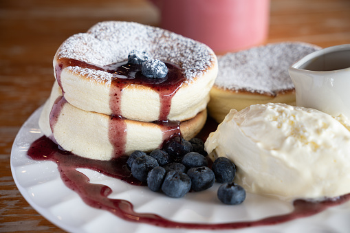 A plate of freshly baked blueberry soufflé pancake served with blueberry sauce and fresh cream.