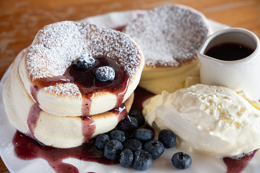 A plate of freshly baked blueberry soufflé pancake served with blueberry sauce and fresh cream.
