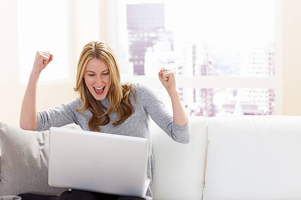 istock Excited young woman cheering while looking at laptop 181120397