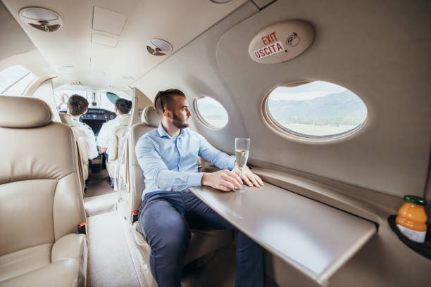 istock Young businessman in a private jet plane, he drinks champagne 1811204909