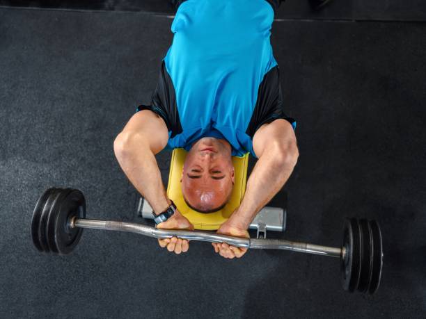 hombre seguro de sí mismo entrenando músculos con barra - body building determination deltoid wellbeing fotografías e imágenes de stock