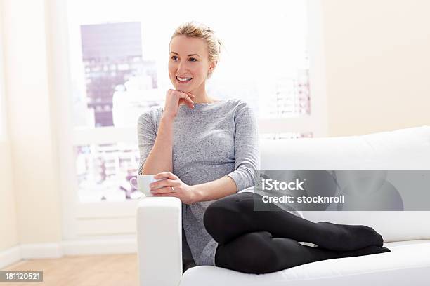Ładna Kobieta Siedzi Na Kanapie Patrząc Od Hotelu Uśmiechnięta - zdjęcia stockowe i więcej obrazów 20-24 lata