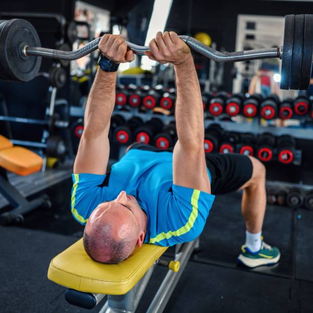 uomo fiducioso che allena i muscoli con il bilanciere - body building determination deltoid wellbeing foto e immagini stock