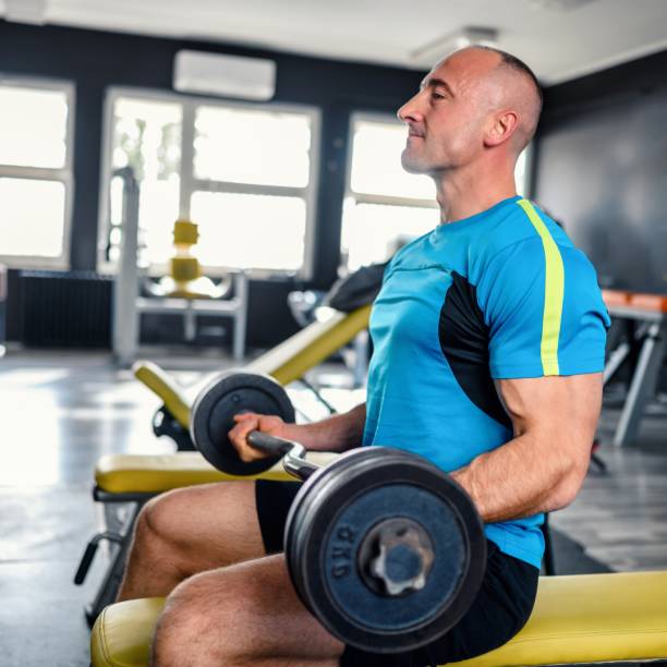 hombre seguro de sí mismo entrenando músculos con barra - body building determination deltoid wellbeing fotografías e imágenes de stock