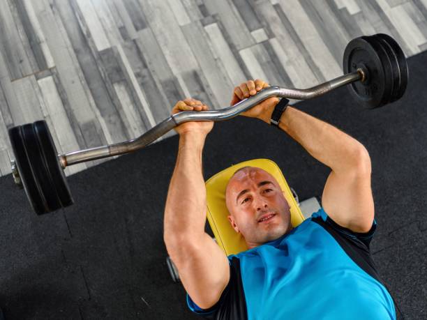 hombre seguro de sí mismo entrenando músculos con barra - body building determination deltoid wellbeing fotografías e imágenes de stock