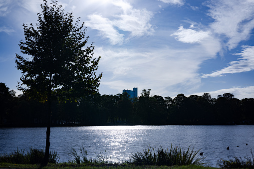 When the cold season approaches, the strong sunlight hots from the side on the city. The lake water surface reflects the rays of the sun in this clear autumn day.