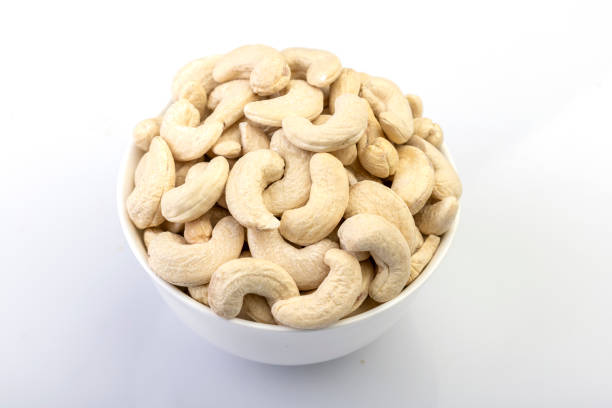 A high-quality image capturing whole cashew nuts neatly arranged in a bowl against a clean white background. The rich texture and natural color of the cashews make this photo perfect for culinary, health, or snack-themed designs.