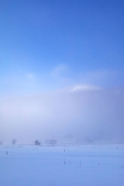 tiefstehende, flauschige wolken auf einer verschneiten wiese im voralpenland - apres ski snow mountain loneliness stock-fotos und bilder