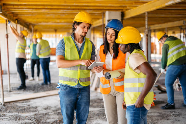 istock Female Engineer Showing The Blueprint On A Tablet To The Construction Workers On A Construction Site 1811249883