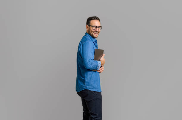 istock Side view of smiling businessman holding wireless computer while posing on isolated white background 1811251022