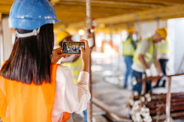istock Female Engineer Taking Pictures Of The Construction Workers On A Construction Site 1811262101