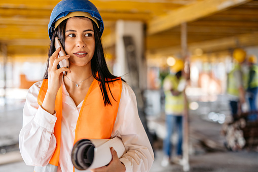Female architect talking on the phone on a construction site (building interior).