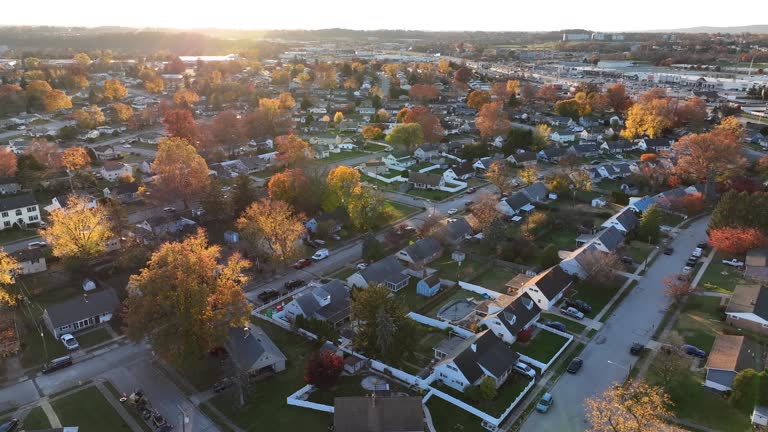 Establishing shot of small town in USA. Colorful autumn fall foliage in neighborhood. Aerial orbit above\ homes and houses in United States of America.