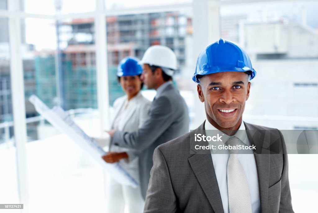Male engineer with colleagues in the background Portrait of a male engineer with colleagues in the background African Ethnicity Stock Photo