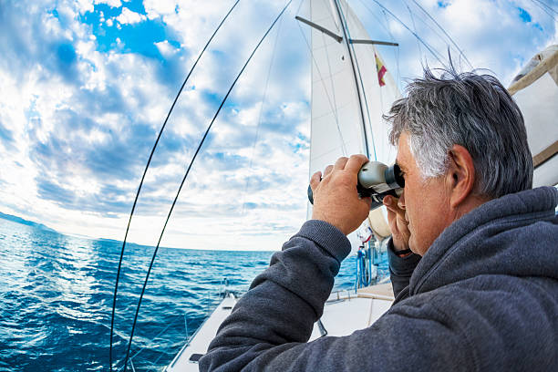 un homme sur un yacht est par le biais de jumelles - water touching sensory perception using senses photos et images de collection