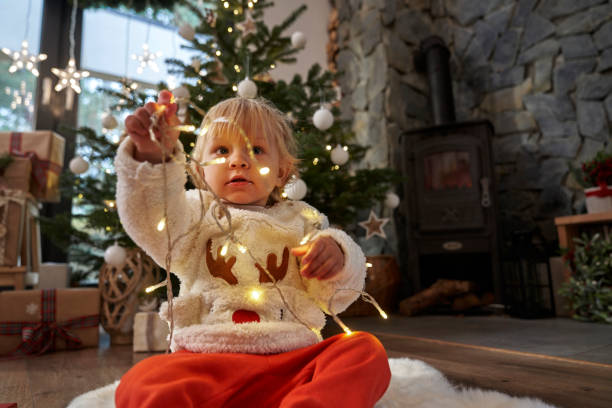 istock Toddler sitting on floor and playing with Christmas lights 1811285307