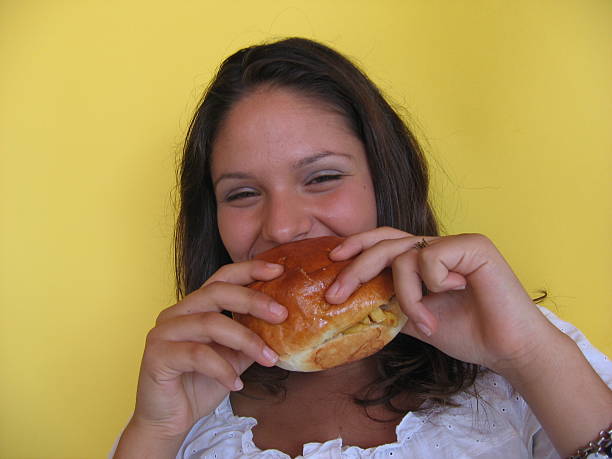 istock young woman eating a sandwich 181128538
