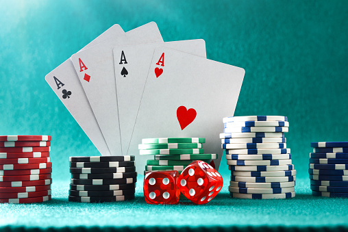 Background with cards chips and dices for playing casino gambling on green felt mat and green isolated background. Front view.