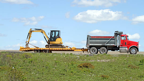 istock A red dump truck towing a yellow excavator 181128774