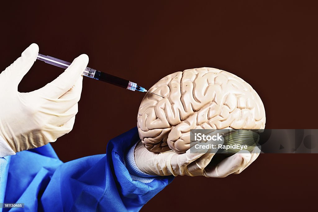 Frankenstein ou cirurgião? As mãos enluvadas Injete um modelo de cérebro - Foto de stock de Acordo royalty-free