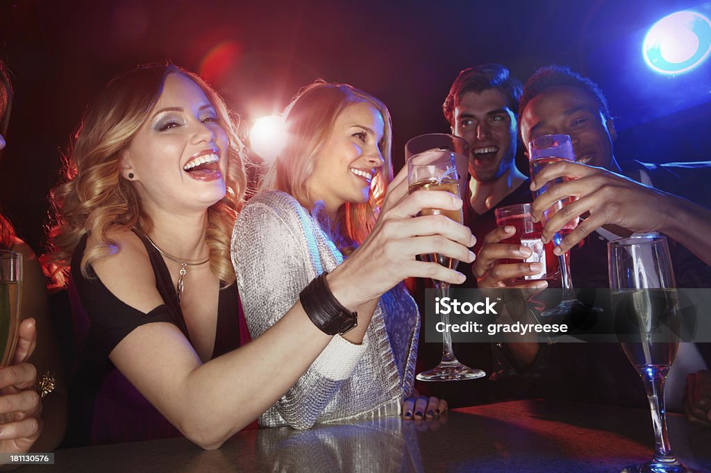 There's always something to celebrate! A multi-ethnic group of friends toasting with their drinks in a nightclub Nightclub Stock Photo