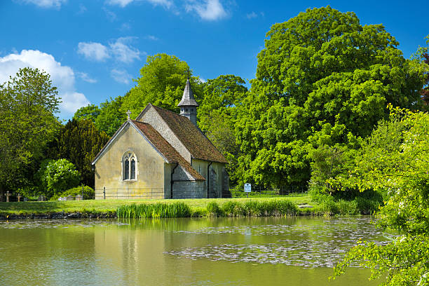 English Country Church St Leonard's Church in the hamlet of Hartley Mauditt, Hampshire. Built in 1100 AD, it's a classic old Norman church surrounded by beautiful English countryside. norman uk tree sunlight stock pictures, royalty-free photos & images