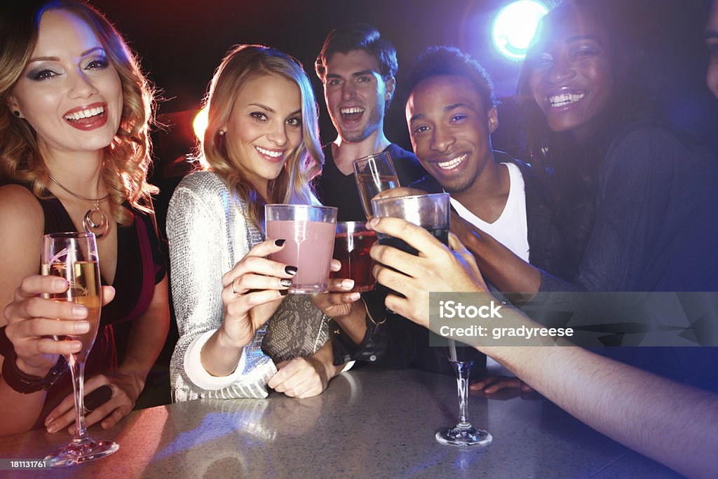 Feeling festive A group of friends smiling at the camera while they enjoy drinks in a nightclub 20-29 Years Stock Photo